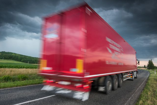 81372446 - red truck on asphalt road under stormy sky with clouds