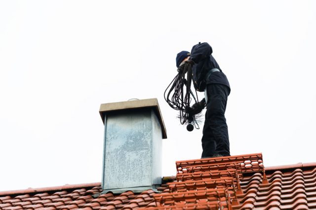 40950683 - chimney sweep standing on roof of home working